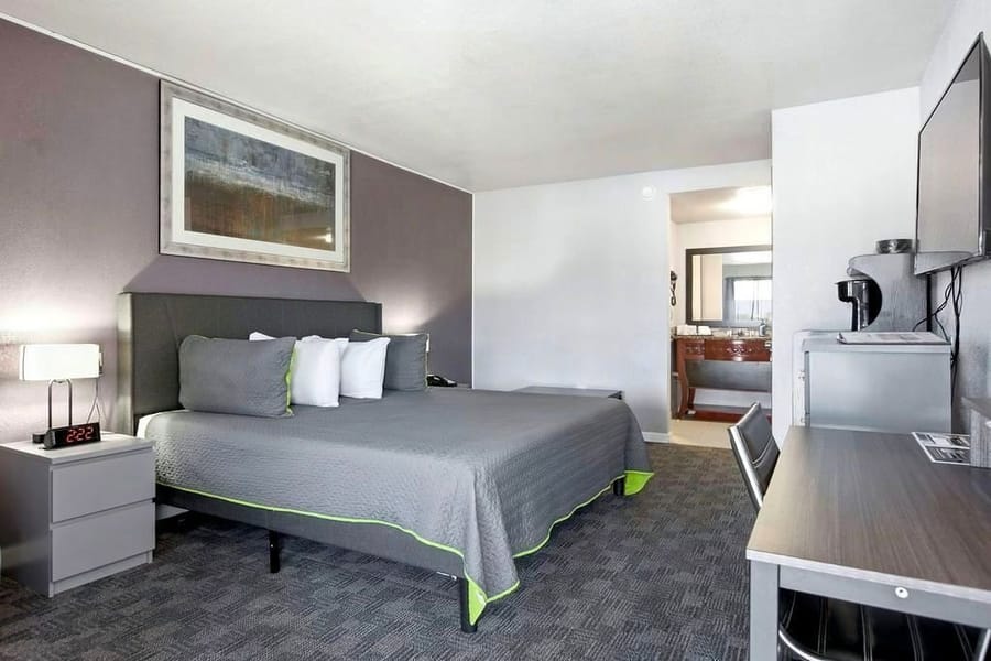 Deluxe King room with a gray bed, framed artwork and a reading chair