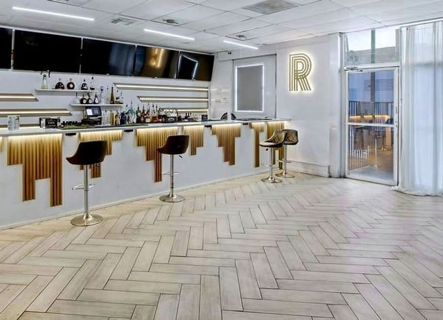 R Lounge bar with a white and gold fluted front, bar stools and backlit shelving
