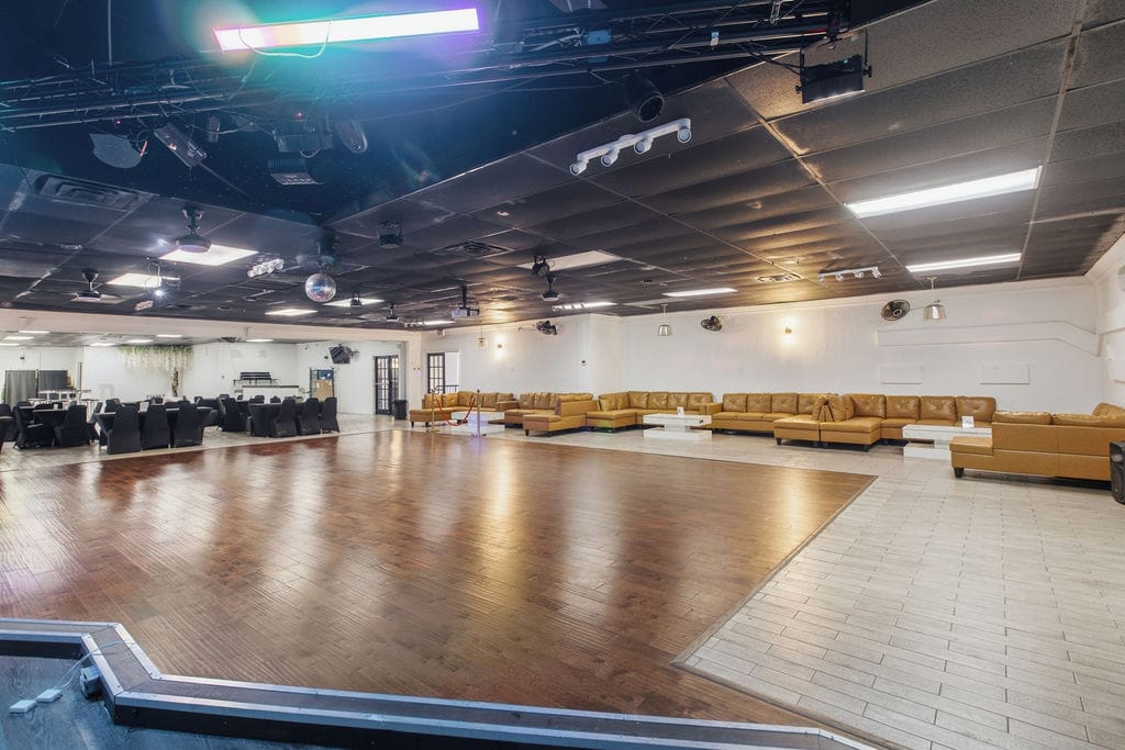 Main event hall at R Nite Star with hardwood dance floor, VIP leather seating, and stage lighting