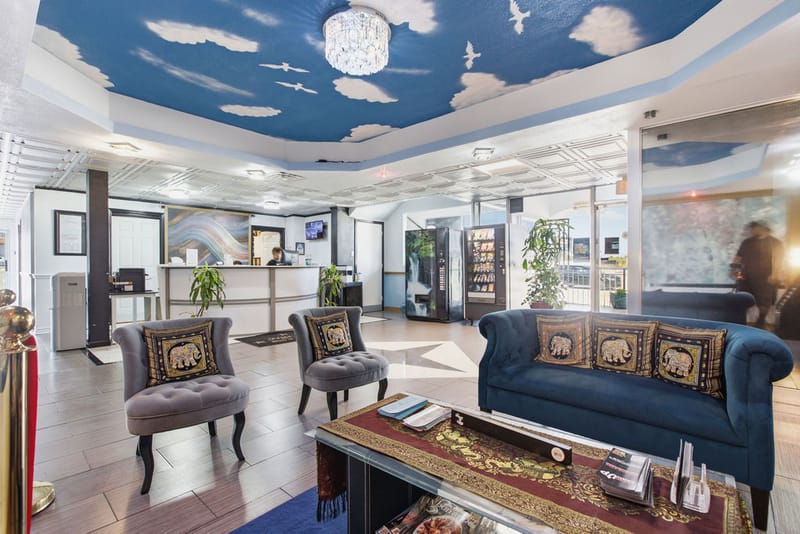 Hotel lobby seating area with blue sofa beneath a hand-painted sky ceiling