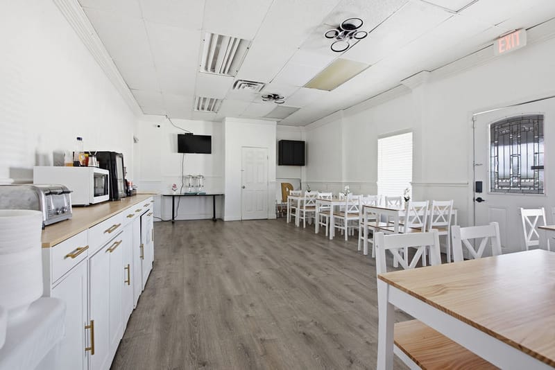 Bright breakfast room with white tables and chairs and a self-serve counter