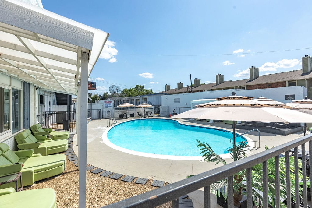 Seasonal outdoor pool seen from the balcony, with green loungers and umbrellas