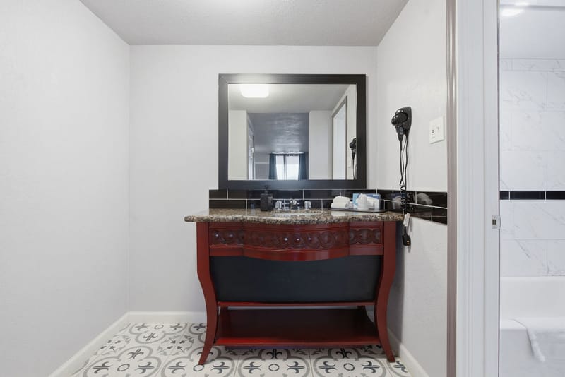 Guest bathroom vanity with granite countertop, dark wood cabinet, and framed mirror