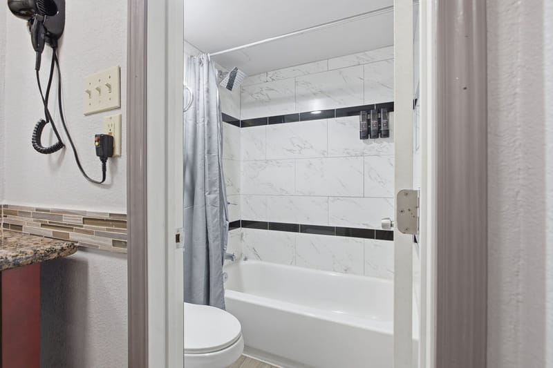 Renovated guest bathroom with marble-look tiled tub and shower combination