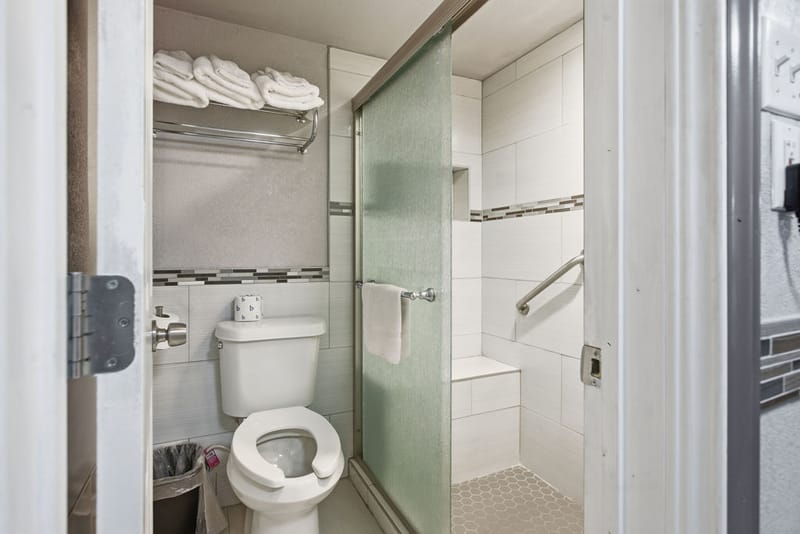 Renovated bathroom with walk-in shower, bench seat, and fresh towels