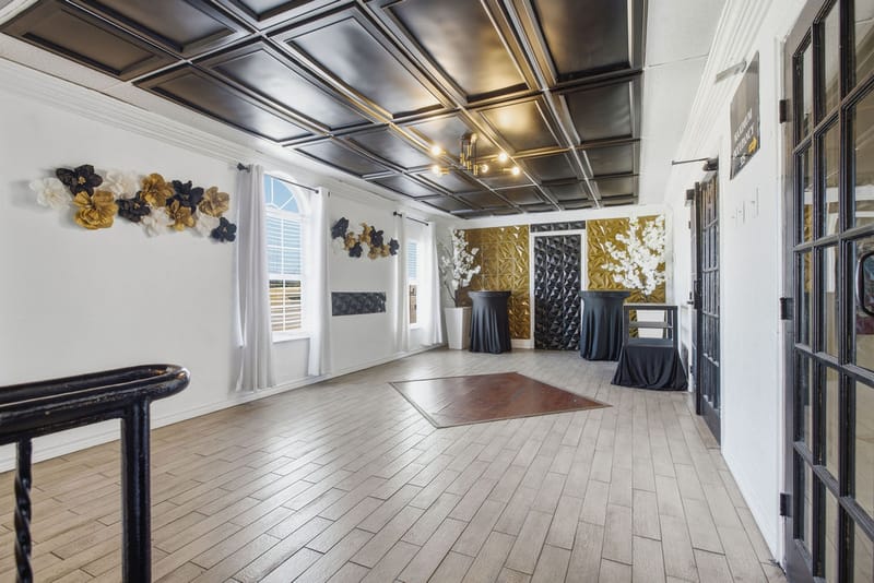 Event foyer with black and gold decor, paper flower wall, and cocktail tables