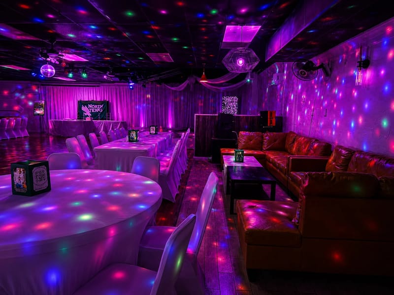 The lounge and event side of the property in use, with banquet tables beside leather lounge seating under colored lighting