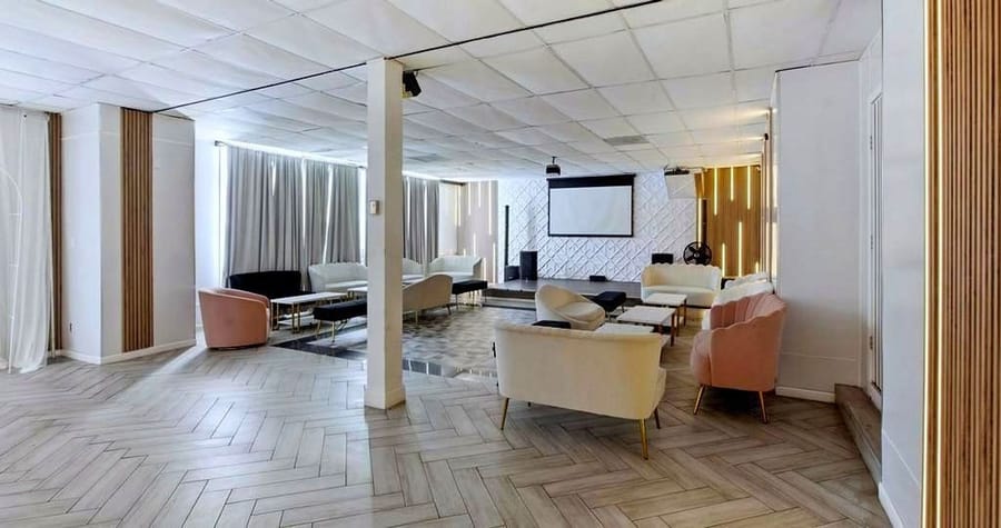 Event space with herringbone floors, pastel armchairs and a projection screen