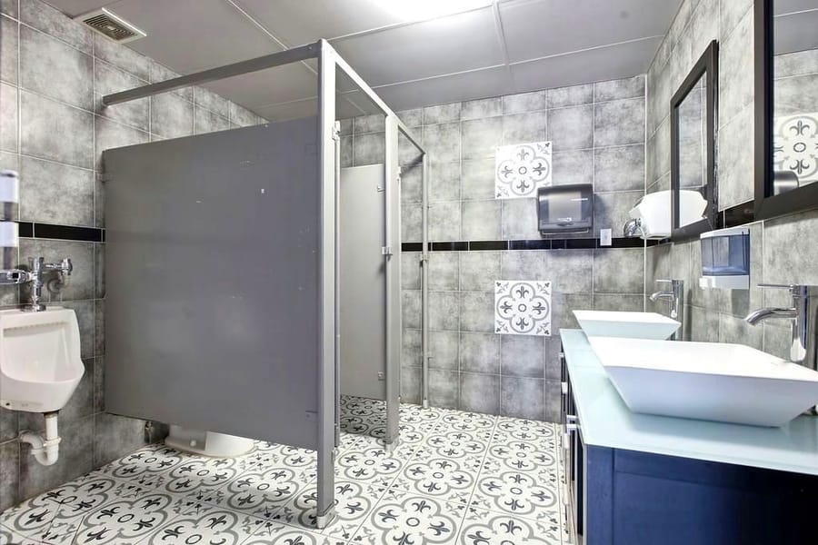 Washroom with vessel basins, patterned tile floor and a framed mirror